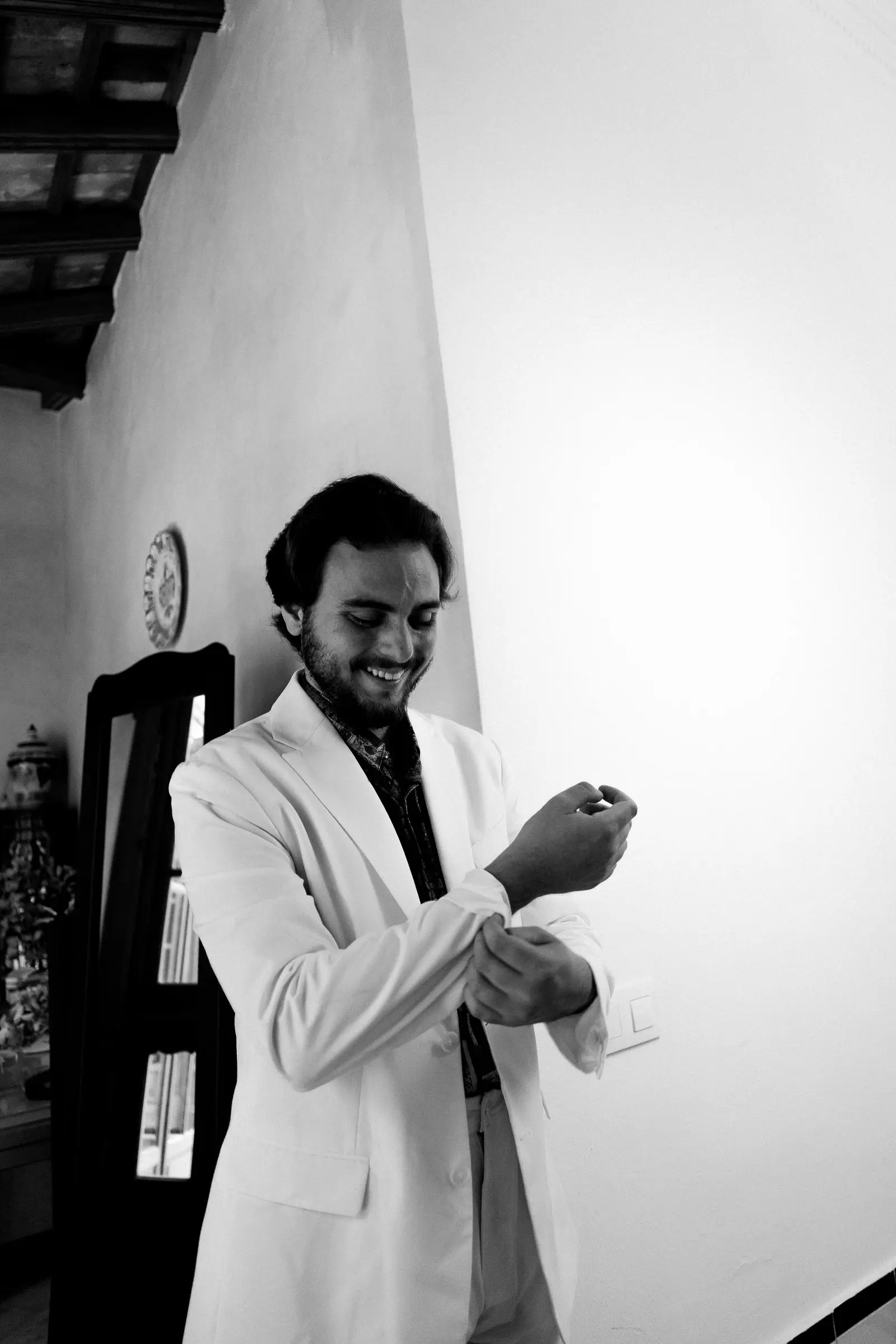 Ajustándose los puños de la camisa, traje blanco